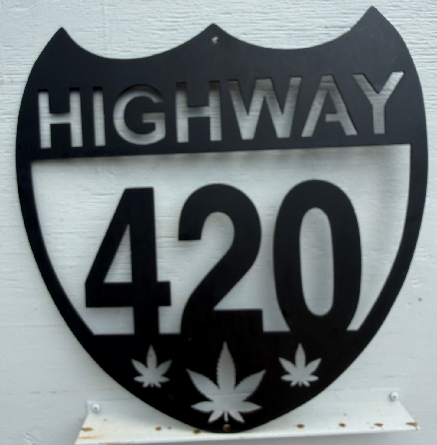 Metal sign shaped like a highway shield with 'HIGHWAY 420' and cannabis leaf symbols on a white background.